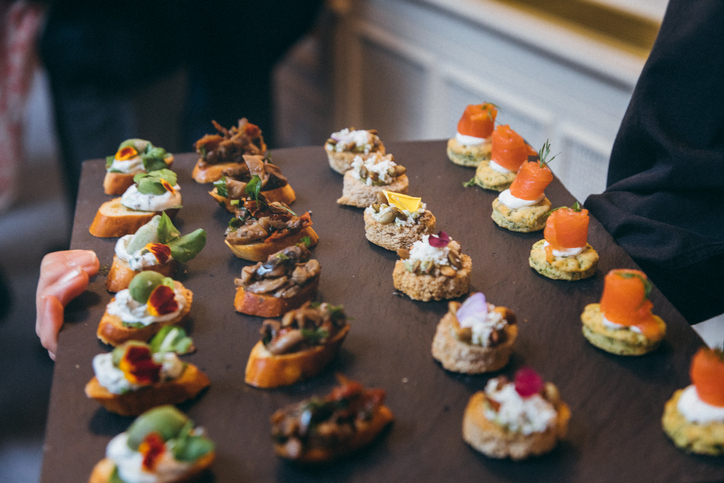 Waiter doing catering service with meat, cheese canepe dish at social gathering festive event party or wedding reception